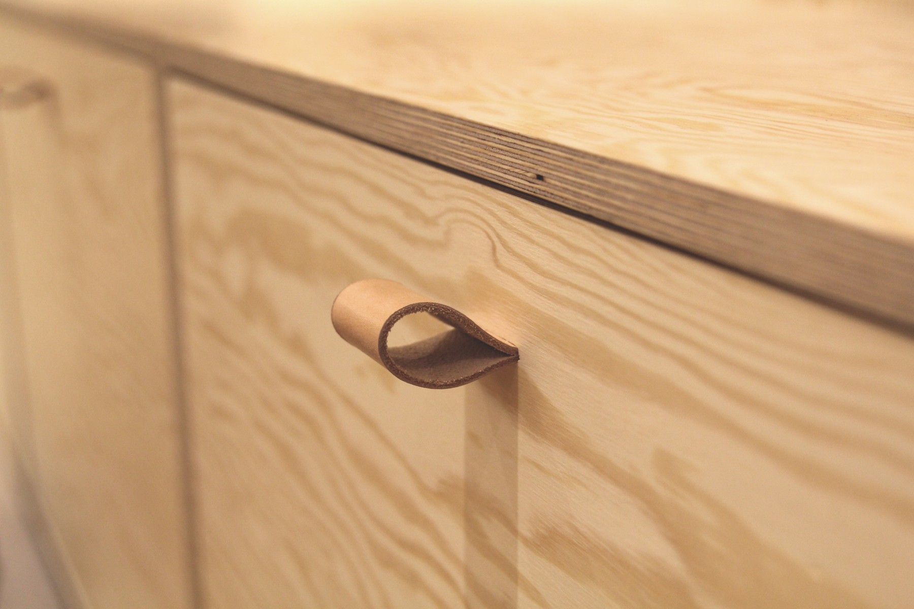 Förvaringslådorna av plywood är måttanpassade efter produkterna och försedda med dolt monterade läderhandtag.